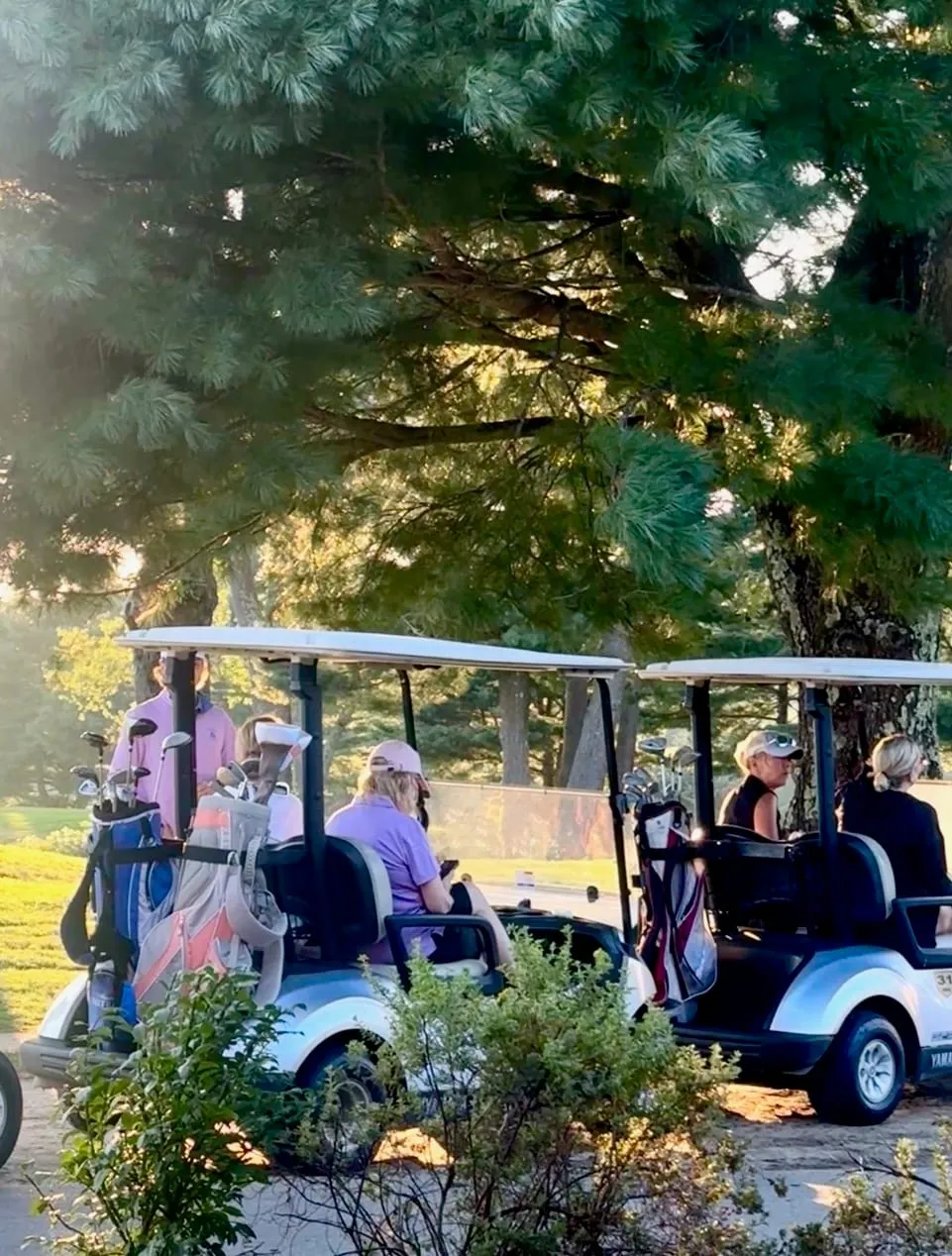 A group of women in golf carts heading out to an on-course lesson